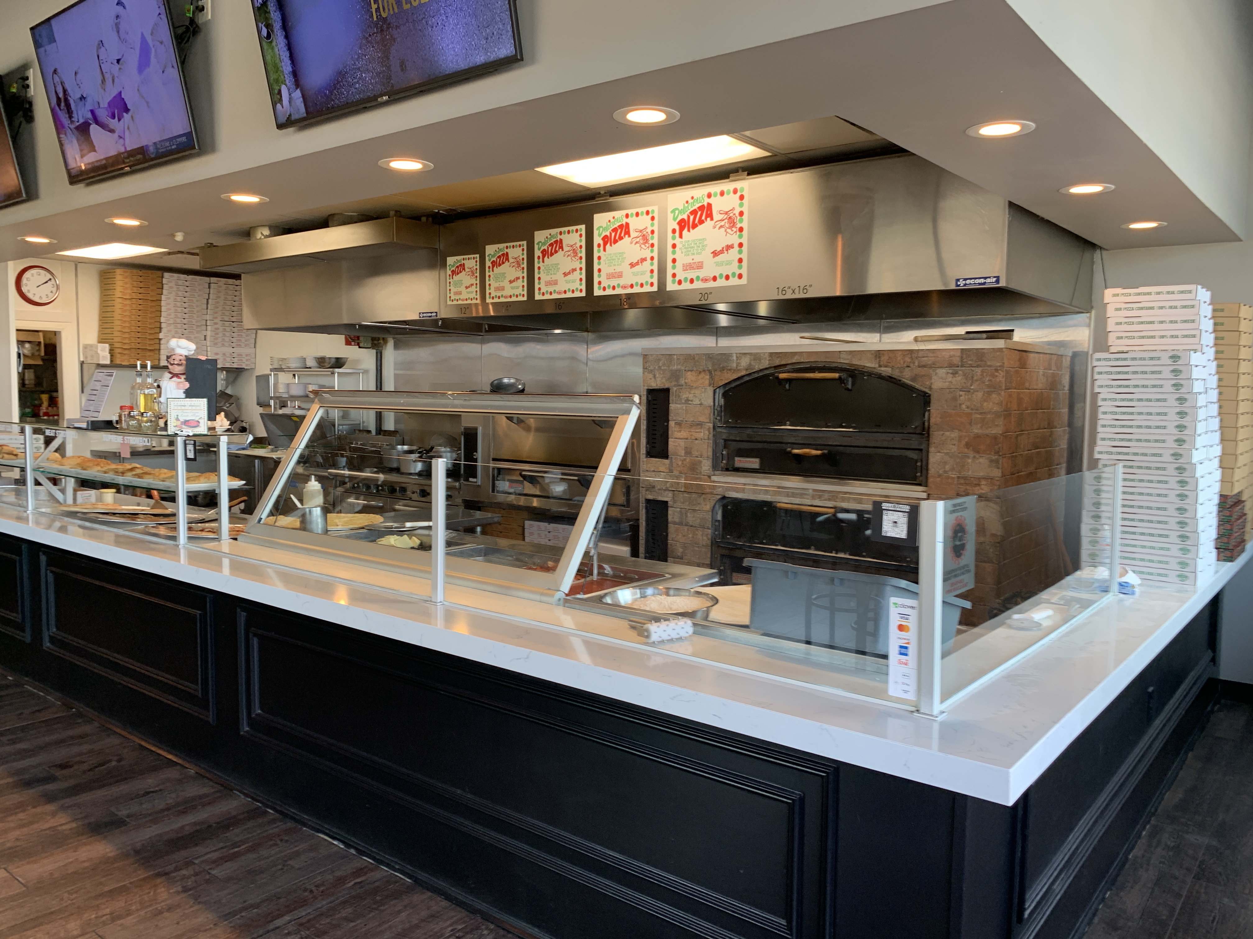 Order counter with pizza size menu boards and stacked to-go boxes at Jonny's Pizza in Aubrey, TX