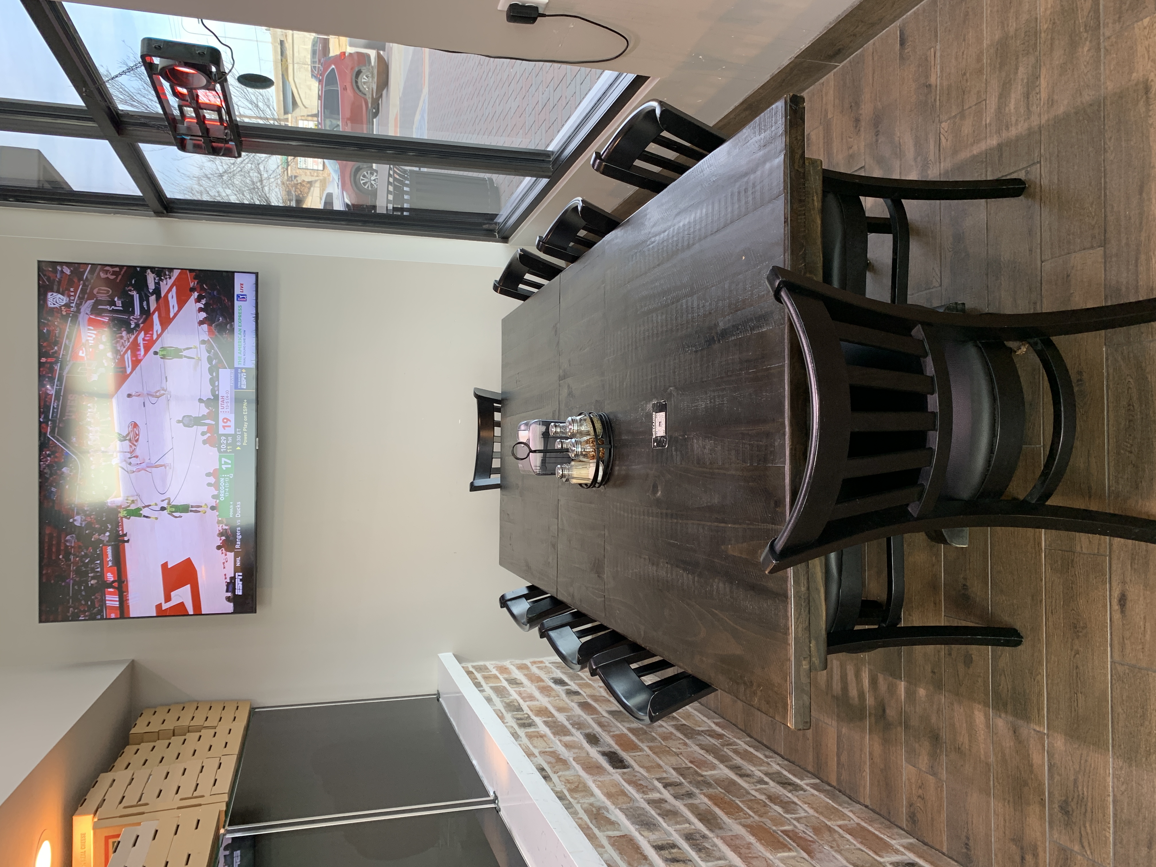 Long communal table for group dining below a TV at Jonny's Pizza in Frisco, TX