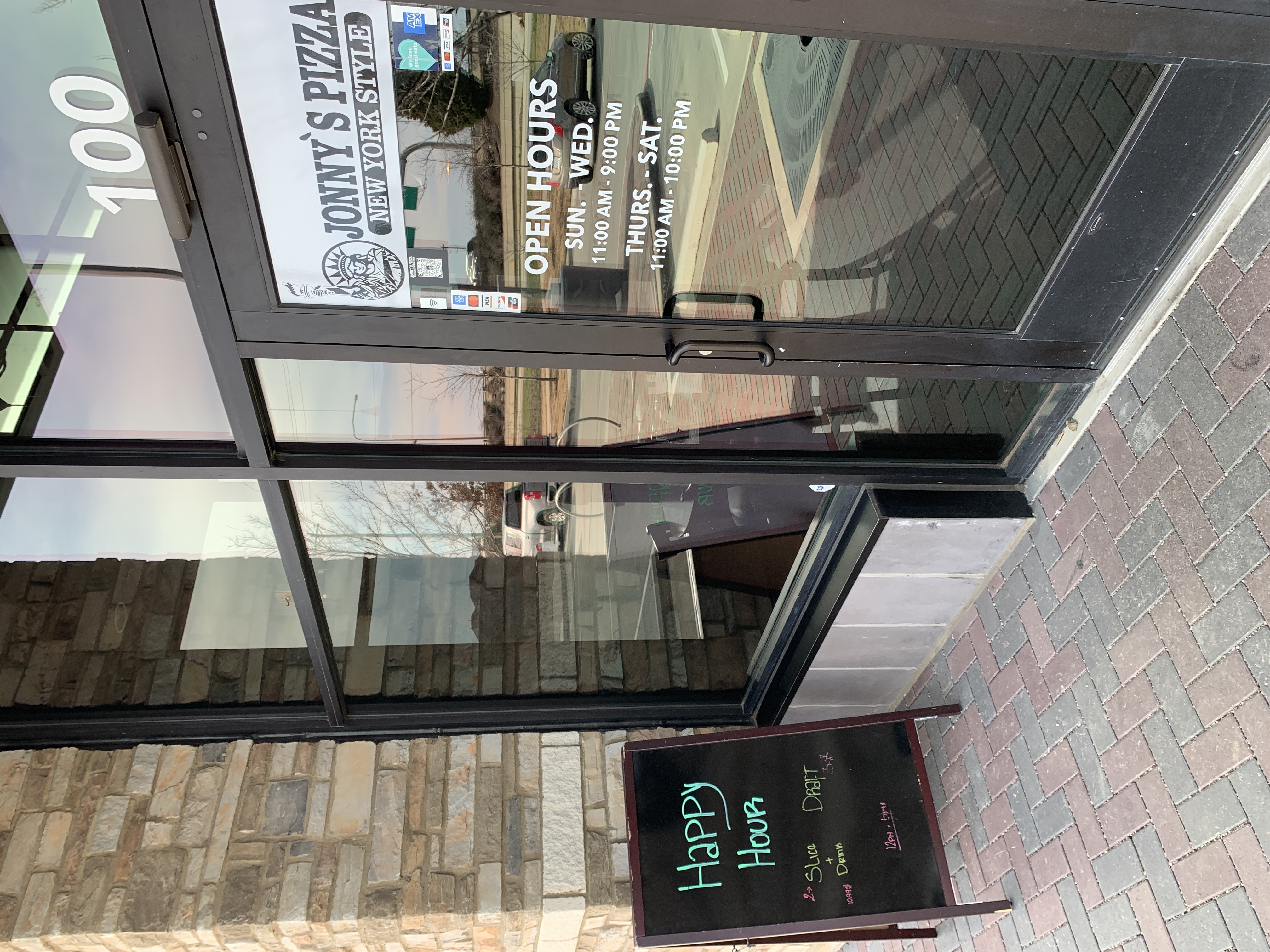 Front entrance and happy hour specials board at Jonny's Pizza in Frisco, TX