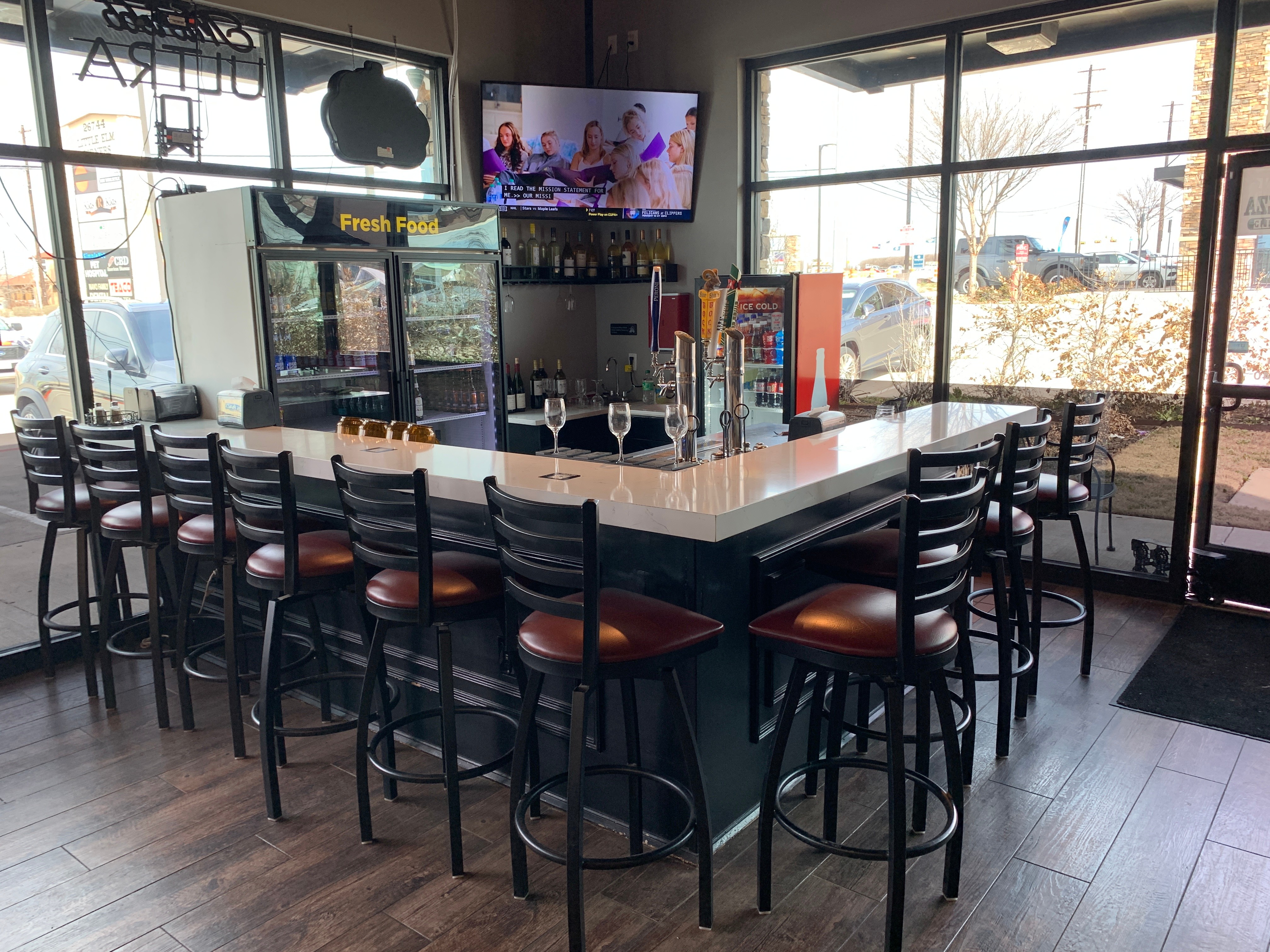 Bar seating with beer taps, wine, and a TV at Jonny's Pizza in Aubrey, TX